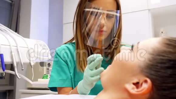 一名女牙医检查一名年轻女子的牙齿视频的预览图