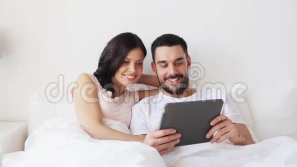带平板电脑的情侣在床上微笑视频的预览图