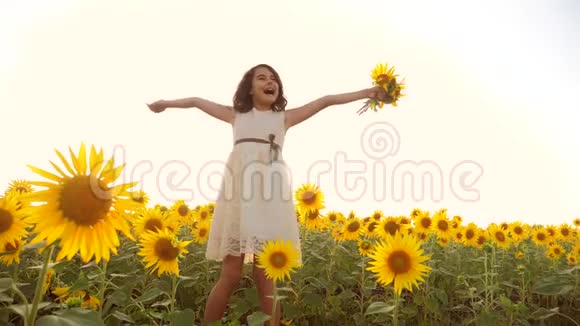 夏天向日葵田野上快乐的小女孩向日葵上美丽的小女孩慢动作视频女孩视频的预览图