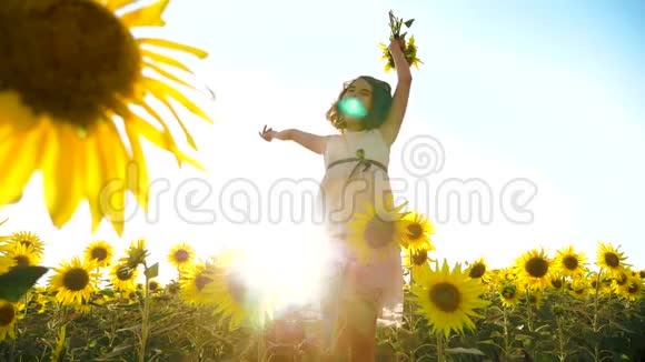 快乐的小女孩在夏天向日葵的阳光下生活方式美丽的日落小女孩向日葵视频的预览图