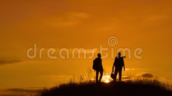 两个男子游客徒步旅行者剪影去山上日落旅游慢动作视频旅行成功的年轻人视频的预览图