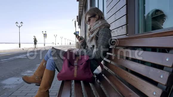 在美丽的公园里的长凳上使用智能手机放松的女人在电话展示中做手势的年轻女子视频的预览图