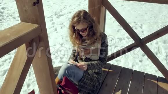 一个年轻的女人坐在木廊上用手指默默地触摸折纸飞机然后把它放在她的身上视频的预览图