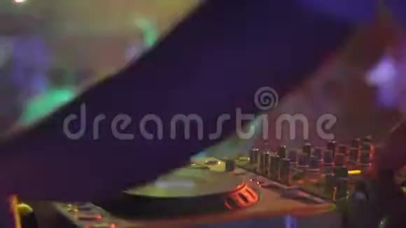 在与跳舞的人举行的夜总会聚会上DJ手和设备视频的预览图
