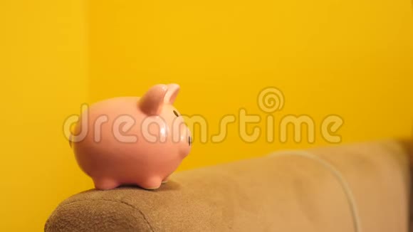 猪银行的经营理念一只手把一枚硬币放在黄色背景下的生活方式储蓄罐里省钱就是视频的预览图
