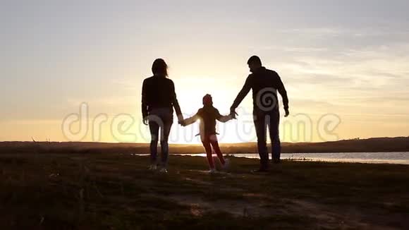 剪影和爸爸妈妈一起快乐的孩子日落时分的家人夏天奔跑在空中养育孩子拥抱爱玩耍视频的预览图