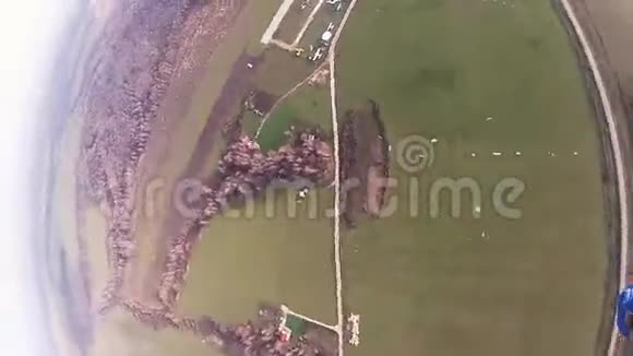 跳伞员跳伞在多云的天空上绿色的田野极限运动景观视频的预览图