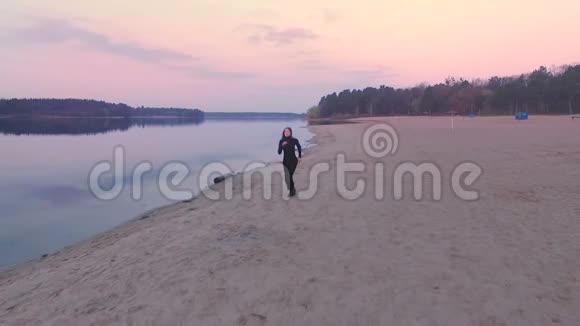 穿黑色衣服的女孩在日出的海滩上奔跑视频的预览图