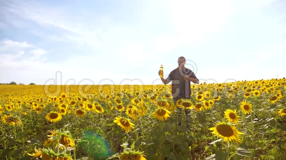 日落时分农夫手捧一瓶葵花籽油男人展示了葵花籽油的生产视频的预览图