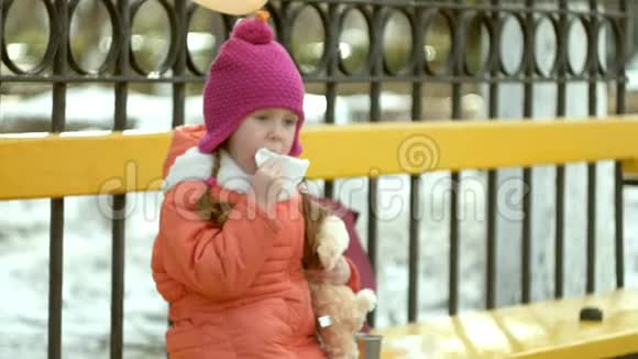 美丽的女孩坐在公园的长椅上吃着美味的甜点视频的预览图