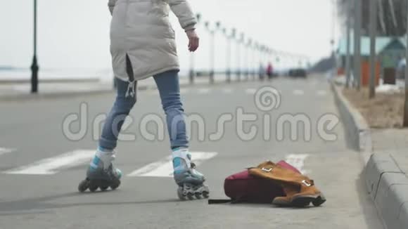 年轻漂亮的女人戴着红帽子穿着运动温暖的衣服和滚筒骑在海岸上的路上视频的预览图