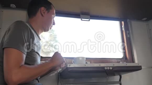 那人坐在火车车厢上手里拿着智能手机喝着咖啡和茶慢速视频视频的预览图