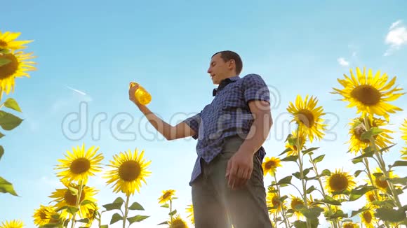 男人手里拿着塑料瓶生活方式葵花籽油站在田野里慢速视频视频的预览图