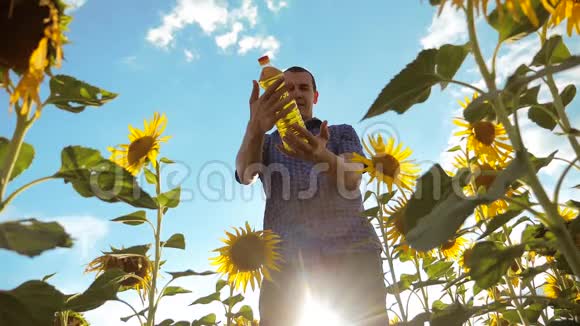 农夫手里拿着一个塑料瓶向日葵油立在田野里慢生活方式运动视频向日葵视频的预览图