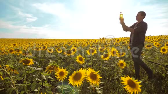 日落时分农夫手捧一瓶生活方式的葵花籽油农民农业塑料瓶视频的预览图