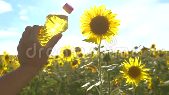 农夫手里拿着一瓶塑料葵花籽油的生活方式在他手里的田野阳光下慢动作视频农业视频的预览图