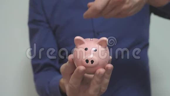 商人使储蓄把硬币放在猪的生活方式罐里储蓄罐的商业概念慢动作视频节省开支视频的预览图