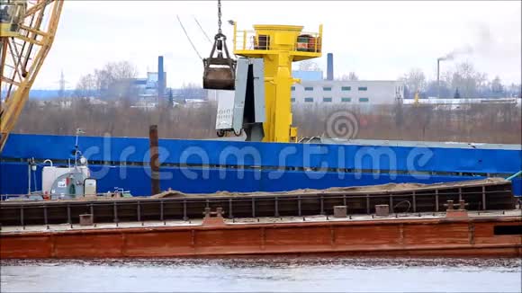 在SevernayaDvina河上用起重机将煤炭从驳船装载到运输船上视频的预览图