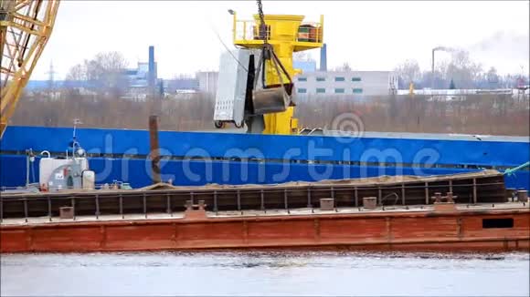 在SevernayaDvina河上用起重机将煤炭从驳船装载到运输船上视频的预览图