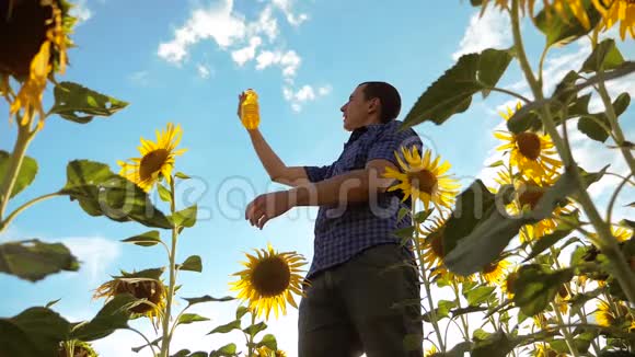 男人手里拿着一个塑料瓶葵花油站在田野里的生活方式慢动作视频向日葵视频的预览图