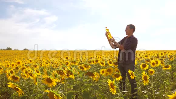 日落时分农夫手捧一瓶葵花籽油慢动作视频农民农业塑料视频的预览图