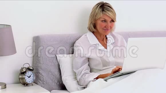 在卧室里用笔记本电脑的成熟女人视频的预览图