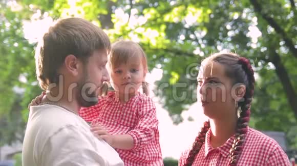 年轻幸福的家庭和小美丽的婴儿蓝色的眼睛走在夏季公园日落视频的预览图