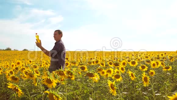 男子农民手捧一瓶葵花籽油在夕阳下的生活方式慢动作视频农民农业视频的预览图