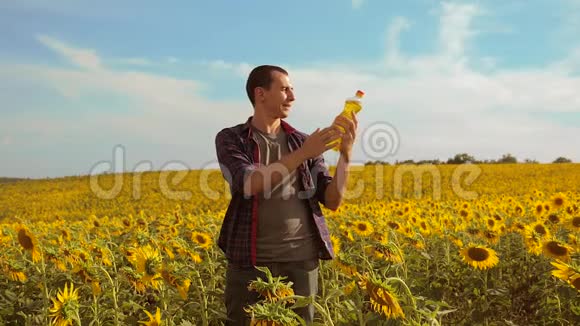 日落时分农夫手捧一瓶生活方式的葵花籽油慢动作视频农民农业视频的预览图