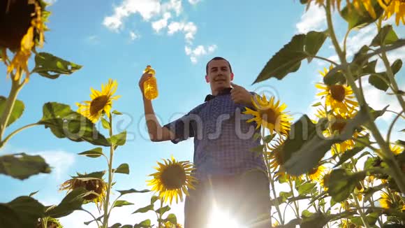 农夫手里拿着一个塑料瓶向日葵油立在田野里慢动作生活方式视频向日葵视频的预览图