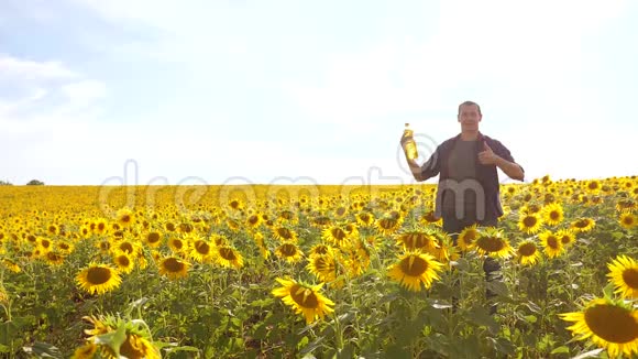 日落时分农夫手捧一瓶生活方式的葵花籽油人类关于葵花籽油生产的节目视频的预览图