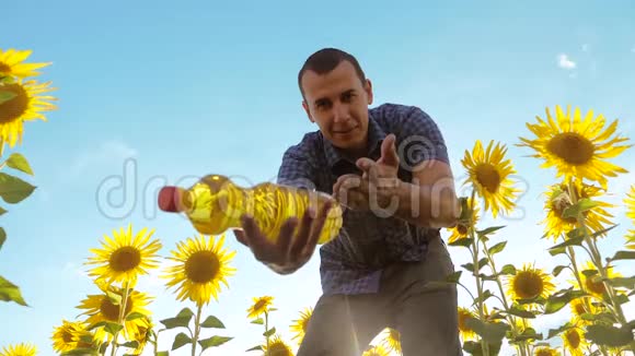 农夫手里拿着一个塑料瓶向日葵油站在田野里慢生活方式视频视频的预览图