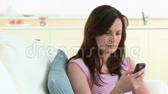 美丽的女人坐在沙发上发短信视频的预览图