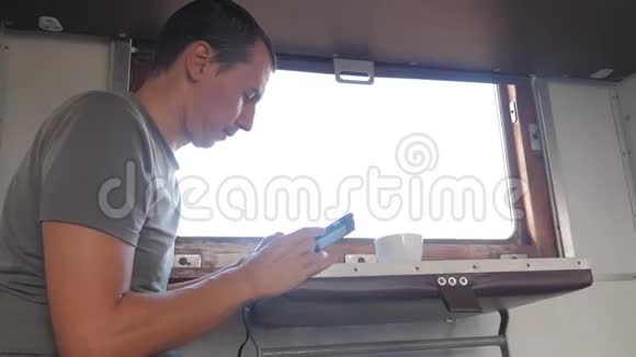 那人坐在火车车厢上手里拿着智能手机喝着咖啡和茶慢速视频视频的预览图