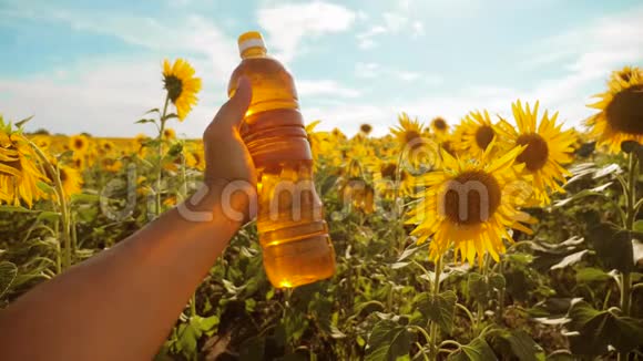 农夫用向日葵在田野里探索农夫手里拿着一瓶塑料葵花籽油视频的预览图