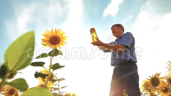 农夫老人手里拿着一个塑料瓶向日葵油立在田野里慢动作视频生活方式视频的预览图