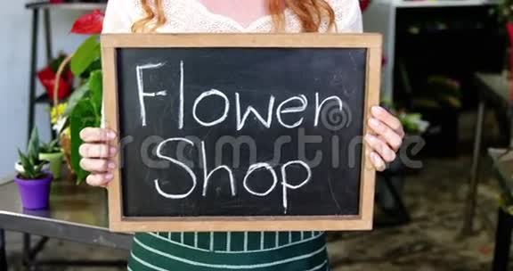 微笑的花匠拿着花店牌子挂在石板上视频的预览图