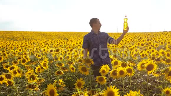 男人的农民生活方式探索田野与向日葵慢动作视频男人的生活方式农民手拿瓶子视频的预览图