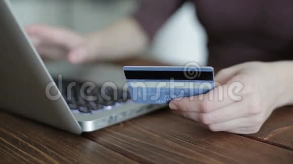 女人用手提电脑拿信用卡视频的预览图