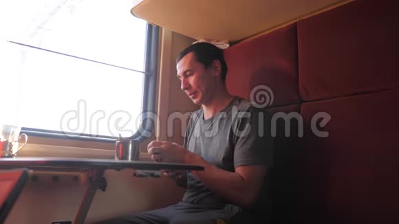 男人坐在火车车厢里拿着智能手机喝着咖啡和茶慢动作视频男人视频的预览图