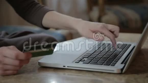 女人用手提电脑拿信用卡视频的预览图