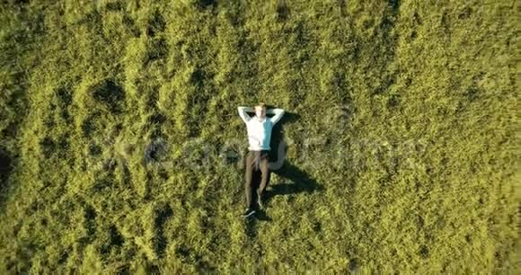 垂直运动飞越商人躺在新鲜的绿色草地上放松的人的最佳景观视频的预览图