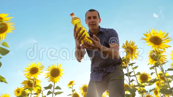 农夫手里拿着一个塑料瓶向日葵油站在田野里慢视频生活方式视频的预览图