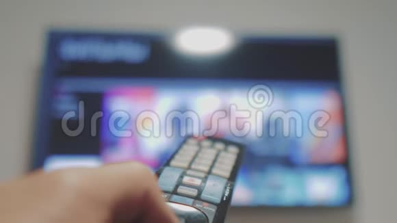 智能电视与应用程序和手男性手握遥控器关闭智能电视男人生活方式手控制电视视频的预览图