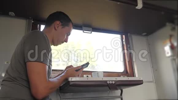 那人坐在火车车厢上手里拿着智能手机喝着咖啡和茶慢生活方式慢生活方式视频的预览图