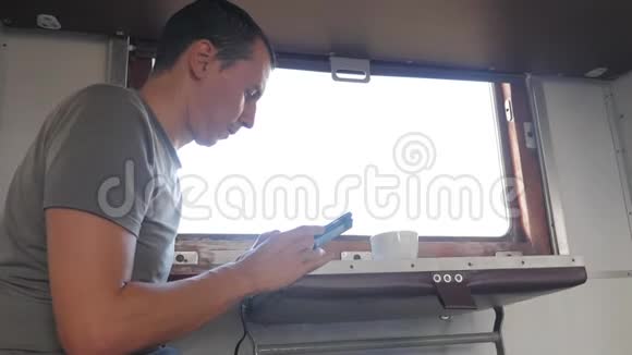 那人坐在火车车厢里拿着智能手机喝着咖啡和茶慢动作视频男人视频的预览图