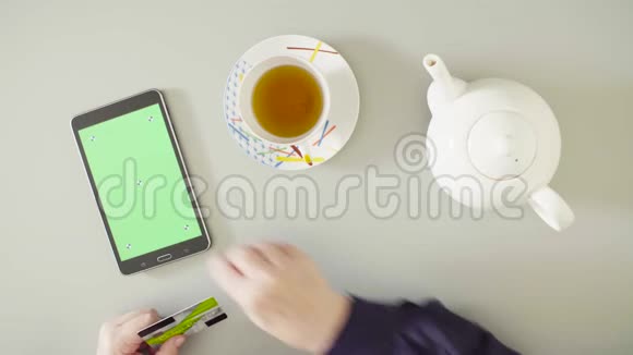 女性手在平板电脑上滚动着绿色屏幕视频的预览图