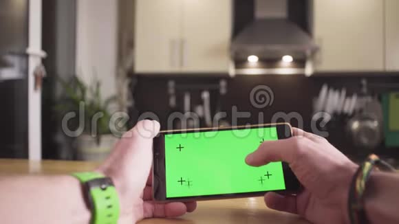 男性手用绿色屏幕滚动智能手机视频的预览图