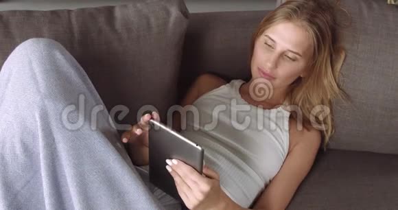 年轻的金发女人在沙发上放松视频的预览图