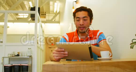 男人在桌上喝咖啡时使用数码平板电脑视频的预览图